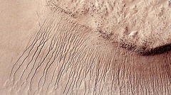 高精細画像で初めて明らかになった火星表面の筋。筋の濃い部分があるのは温暖な季節に水が流れていることを示す痕跡とみられる