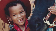 カウボーイハットをかぶり、なついている馬と撮影した子どものころの写真＝クレイ氏提供