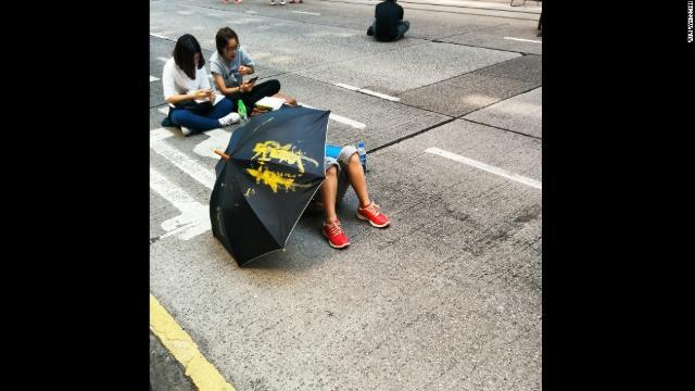 傘を広げて地面に寝転ぶデモ参加者。期限を迎えた６日もデモが続いている