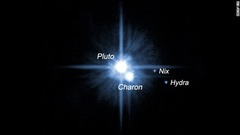 冥王星とその近くで明るく輝くカロン＝NASA/ESA提供