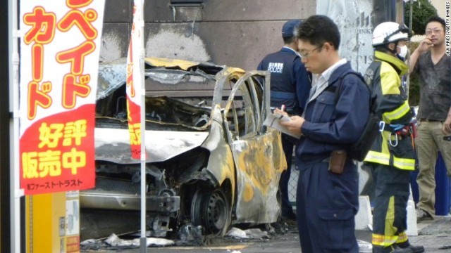 爆発の影響で大破した車両を調べる捜査関係者ら