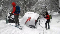 雪崩の直撃を受けたリゴピアノホテルの前で雪に埋もれた２台の車。そばにいるのは救助隊員
