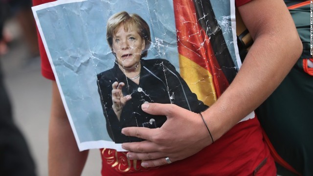 ドイツのメルケル首相の写真を手にしたシリア難民