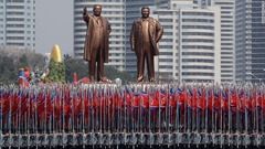 北朝鮮国旗を持って像の前に立つ大学生