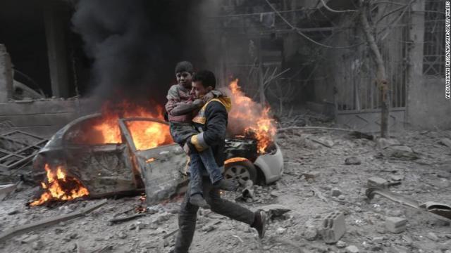空爆を受けて負傷した子どもを運ぶ男性