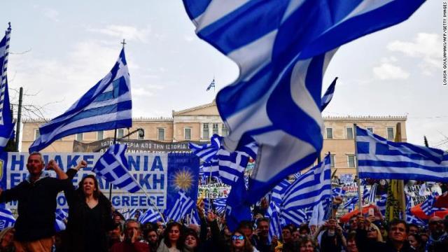 アテネでギリシャ国旗を掲げて抗議する人々