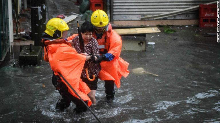 女性を助ける救急隊員＝１６日、香港/Anthony Wallace/AFP//Getty Images