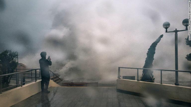 高波の様子を撮影する男性＝１６日、香港/Anthony Kwan/Bloomberg/Getty Images