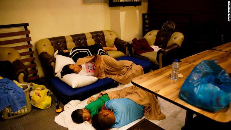 嵐のための屋根が破損し、ホテルのレストランで寝る人たち＝１５日、フィリピン・トゥゲガラオ/Aaron Favila/AP