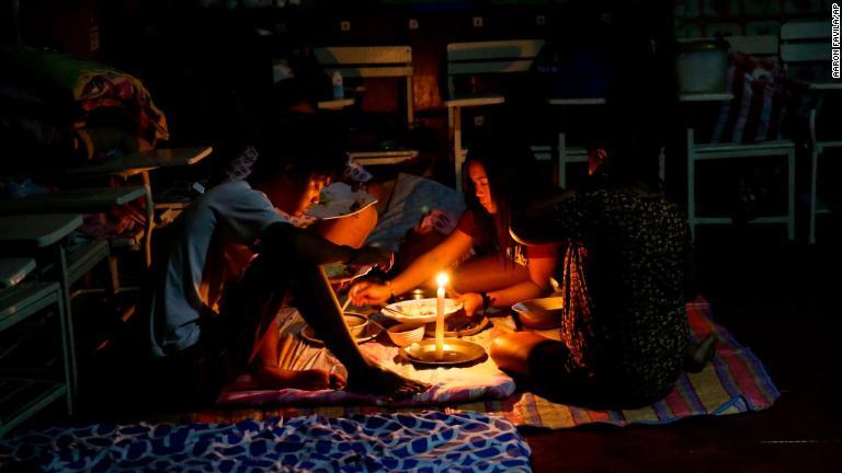 避難シェルターで食事を分け合う家族＝１５日、フィリピン・トゥゲガラオ/Aaron Favila/AP