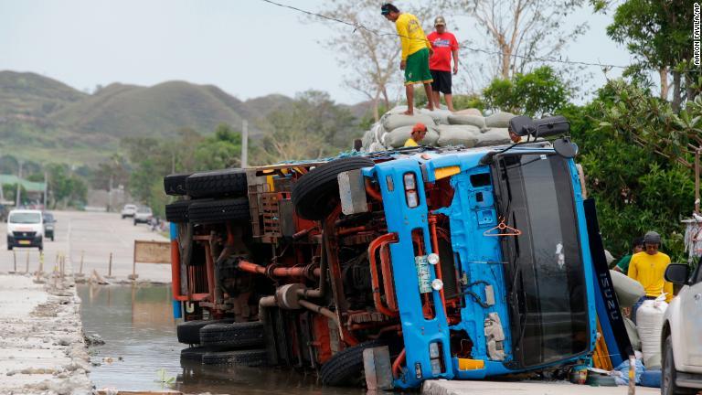転倒したトラックから荷物を運び出す人たち＝フィリピン北東部/Aaron Favila/AP