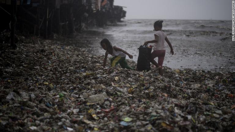 海岸に打ちあがられたものを拾う子どもたち＝１５日、マニラ/NOEL CELIS/AFP/AFP/Getty Images