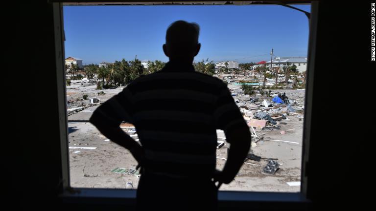 自宅から被災した周囲の様子を見る男性＝１２日、フロリダ州メキシコビーチ/Hector Retamal/Getty Images