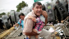 子どもを守るホンジュラスの男性。移民集団の一部が検問所を突破した＝１９日