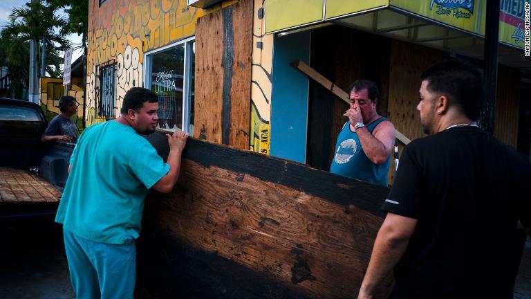 店の窓に板を打ち付ける男性＝２７日、プエルトリコ・ボケロン/Ramon Espinosa/AP