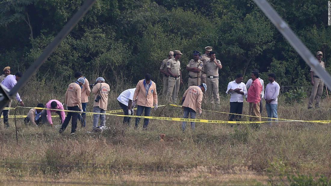 容疑者が射殺された現場の検証を行う法医学の専門家とそれを見守る警察官/Mahesh Kumar A/AP