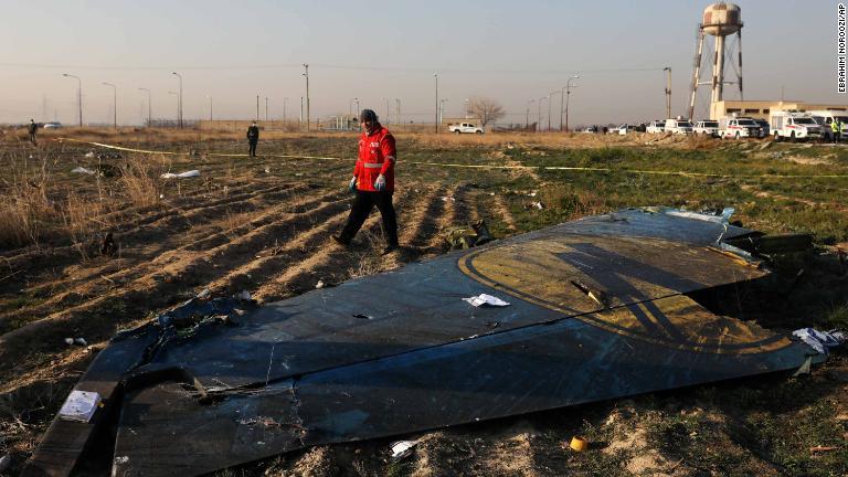 飛行機の残骸を通りすぎる隊員/Ebrahim Noroozi/AP