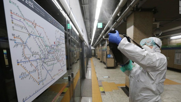 防護服を身に着けソウルの地下鉄で予防措置として消毒剤をまく作業員＝２１日/Ahn Young-joon/AP