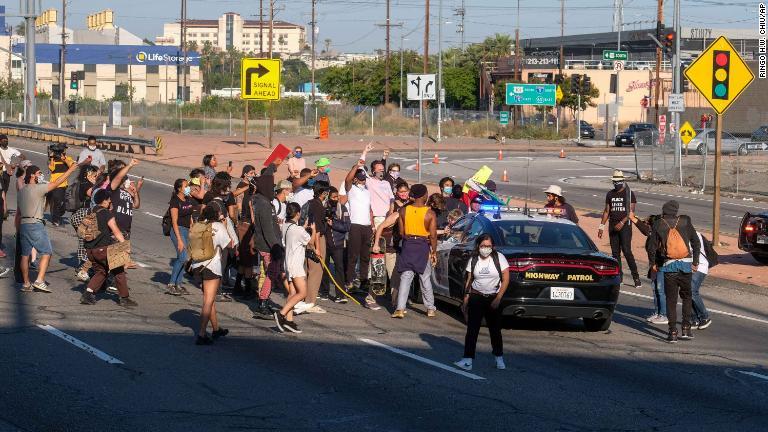カリフォルニア州高速道路警察の車両にデモ参加者らが集まってくる/Ringo H.W. Chiu/AP