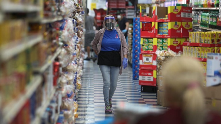 感染防止のための防護具を着用して勤務するフロリダ州マイアミのスーパーの店員/Joe Raedle/Getty Images 
