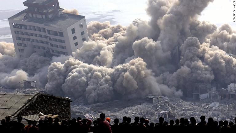 建物の破壊の様子を見る住民ら＝２００２年/AFP/Getty Images