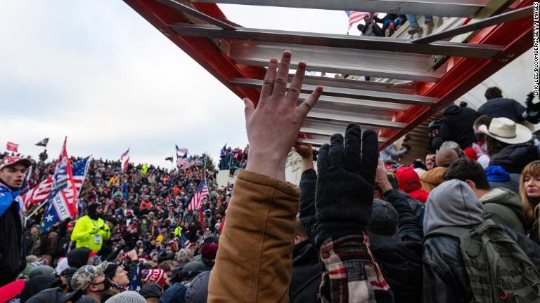 議事堂に押し入る人々を助けようとはしごを持ち込む人々/Eric Lee/Bloomberg/Getty Images
