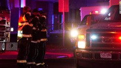 銃撃現場を去る救急車に敬礼する消防士