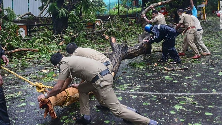 ゴア州パンジムで倒木を取り除こうとする警官＝１６日/Umesh Zarmekar/AFP/Getty Images