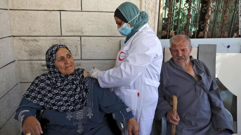 ヨルダン川西岸地区で医療従事者からワクチンを投与されるパレスチナの女性/HAZEM BADER/AFP/AFP via Getty Images