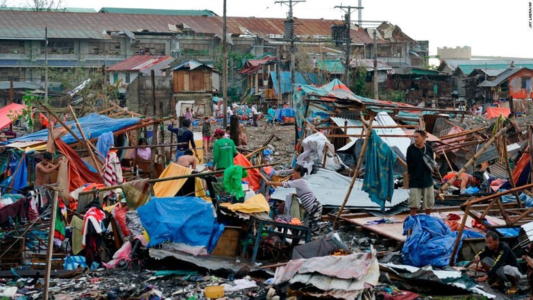 倒壊した自宅から残ったものを回収する住民ら/Jay Labra/AP