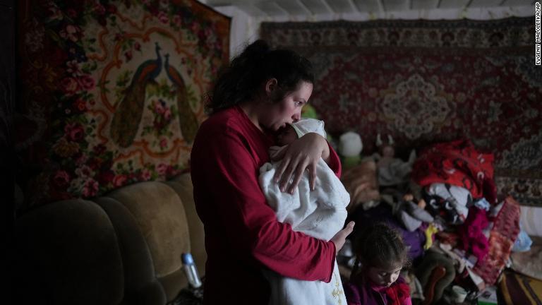 ウクライナ東部ノボフナティブカで分離独立勢力による砲撃とされる攻撃後に生後２カ月の息子をあやす女性＝２０日/Evgeniy Maloletka/AP
