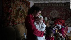 ウクライナ東部ノボフナティブカで分離独立勢力による砲撃とされる攻撃後に生後２カ月の息子をあやす女性＝２０日