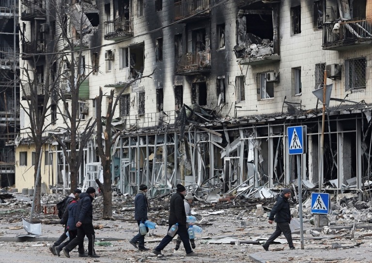 マリウポリの破壊された建物を通り過ぎる住民＝３日/Alexander Ermochenko/Reuters