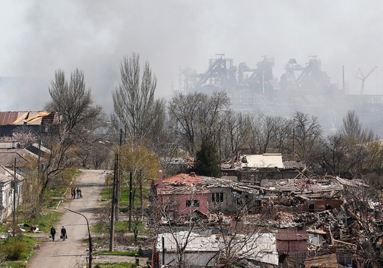 倒壊した建物の向こう、煙の中に浮かび上がるアゾフスターリ製鉄所の施設/Alexander Ermochenko/Reuters