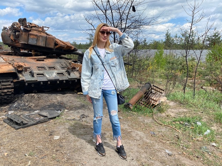 ブチャに住む母親を訪ねる途中、さびついた戦車の前に立つ慈善団体職員の女性/Ivana Kottasova/CNN