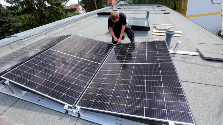ドイツの住宅の屋根にソーラーパネルを設置する作業員/Wolfgang Kumm/picture-alliance/dpa/AP
