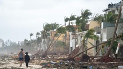 被害の状況を見ながら浜辺を歩く人々＝２９日、米フロリダ州ボニータ・スプリングス