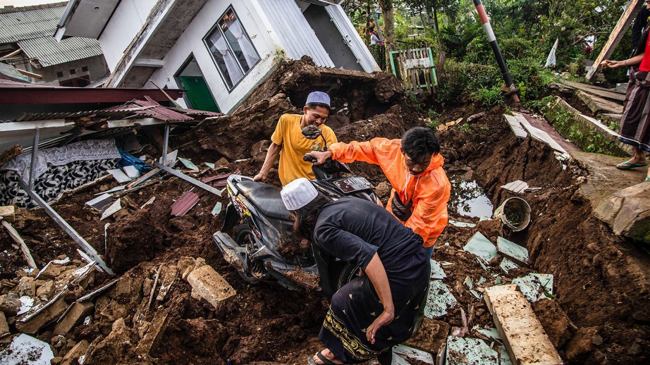 倒壊した建物から物品を運び出す住民＝２２日、チアンジュール/Aditya Aji/AFP/Getty Images