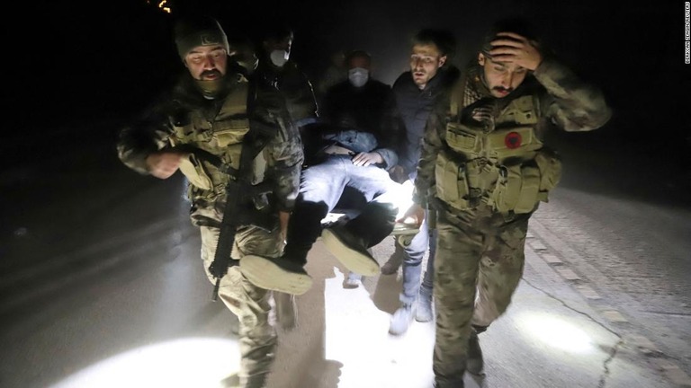 ２０日、トルコ南部で新たに発生した地震により負傷した男性を運ぶ救助隊員ら/Berkcan Zengin/Reuters