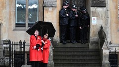 ５日、雨宿りする英国会議事堂の職員と警官