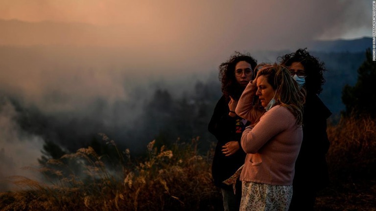 村に迫る山火事を見守る住人ら＝２５日、ポルトガル・カスカイスのザンブジェイロ村/Patricia De Melo Moreira/AFP/Getty Images