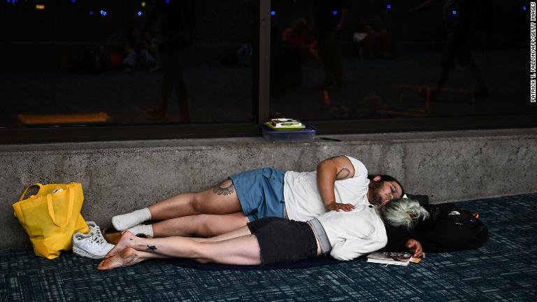 カフルイ空港でフライトを待ちながら眠ろうとする人たち＝８月９日/Patrick T. Fallon/AFP/Getty Images