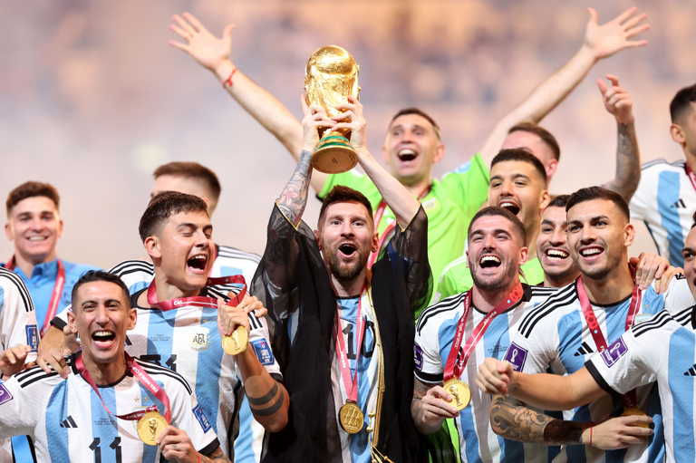 ２０２２年サッカーのワールドカップ（Ｗ杯）カタール大会でアルゼンチンが優勝し、トロフィーを高く掲げるリオネル・メッシ（中央）とアルゼンチンの選手ら/Julian Finney/Getty Images