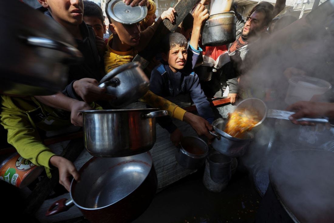 食料を受け取るため空の容器を持つパレスチナの人々＝１２月２日、パレスチナ自治区ガザ地区ラファ/braheem Abu Mustafa/Reuters