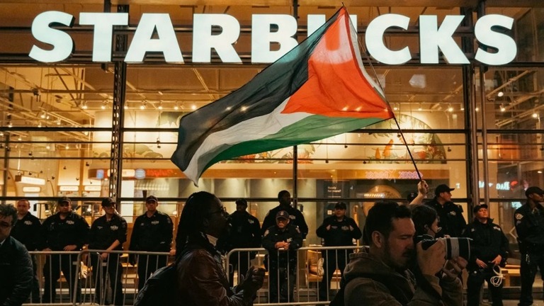 パレスチナ支持のデモ隊が通過する米ＮＹのスターバックス店舗前で警備に立つ警官隊/Cristina Matuozzi/Sipa USA