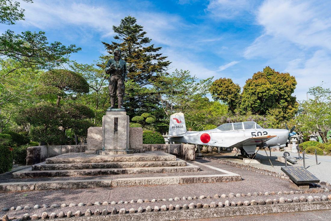知覧特攻平和会館の外に展示された日本の軍用機。特攻隊員の像と共に/World Discovery/Alamy Stock Photo