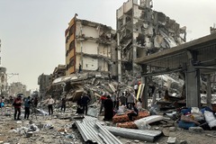 イスラエル軍による攻撃で破壊された建物の周りに集まるパレスチナ人たち