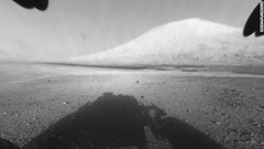 キュリオシティが目指す「シャープ山」。手前に機体の影が見える。遠方の黒っぽい帯は砂丘とみられる　(C)NASA/JPL-Caltech