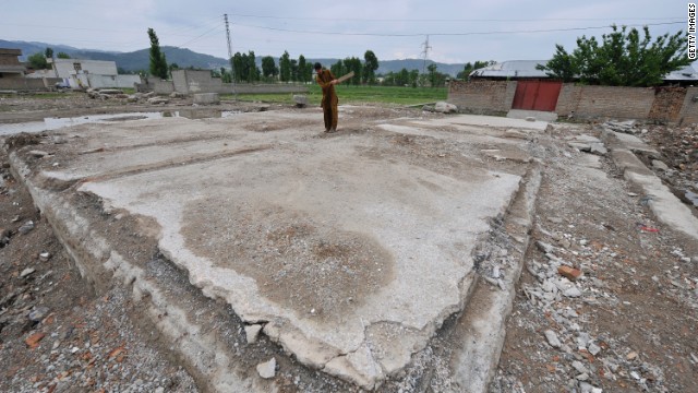 邸宅の跡地でクリケットの練習をする少年