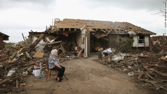 知人宅の前に座る女性。この家も竜巻で破壊された